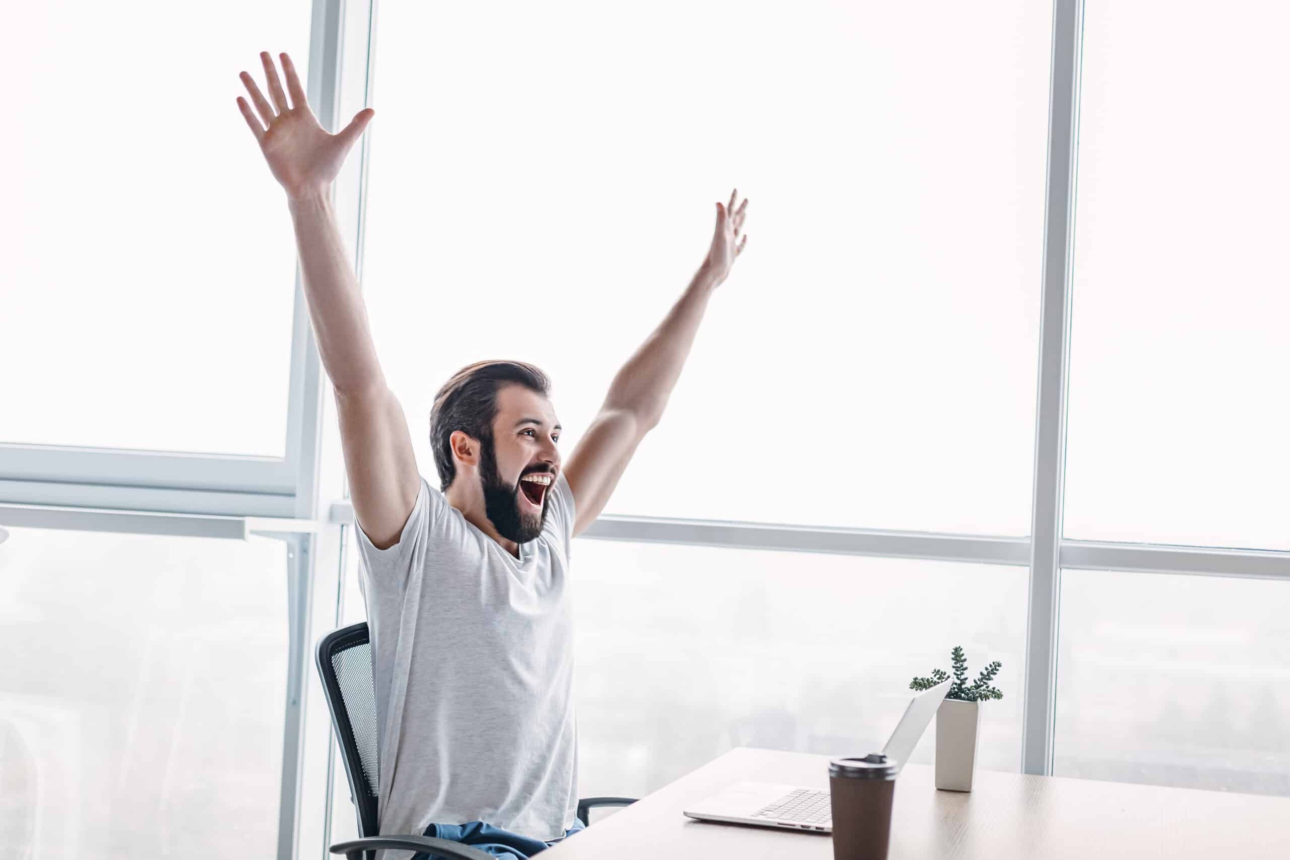 handsome darkhaired businessman celebrating success with arms raised while looking away side view scaled